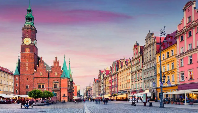 Colorful townhouses and a clock-towered town hall around a cobbled European square.