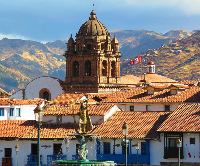 A church tower and red-tiled rooftops beneath mountains in Peru.