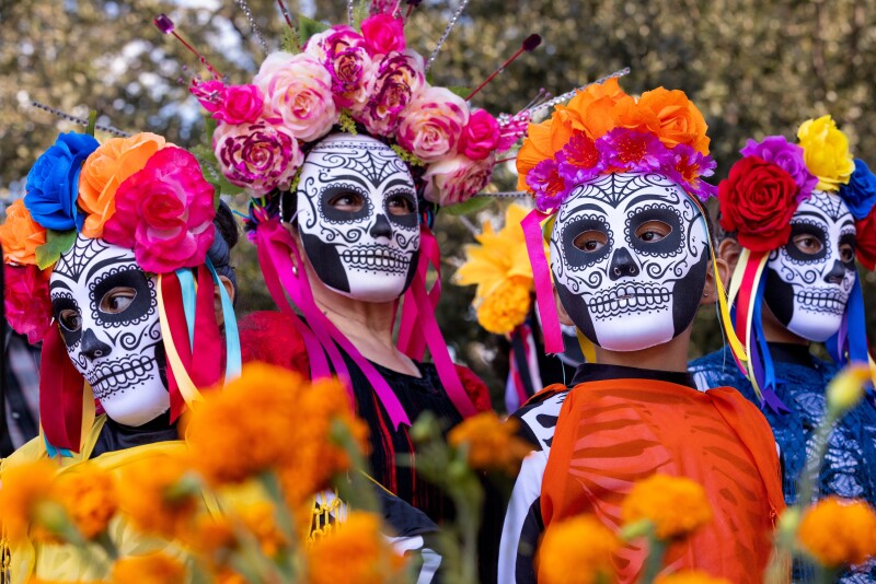 Skull face paint, bright flowers and ribbons celebrating Day of the Dead traditions in Oaxaca.