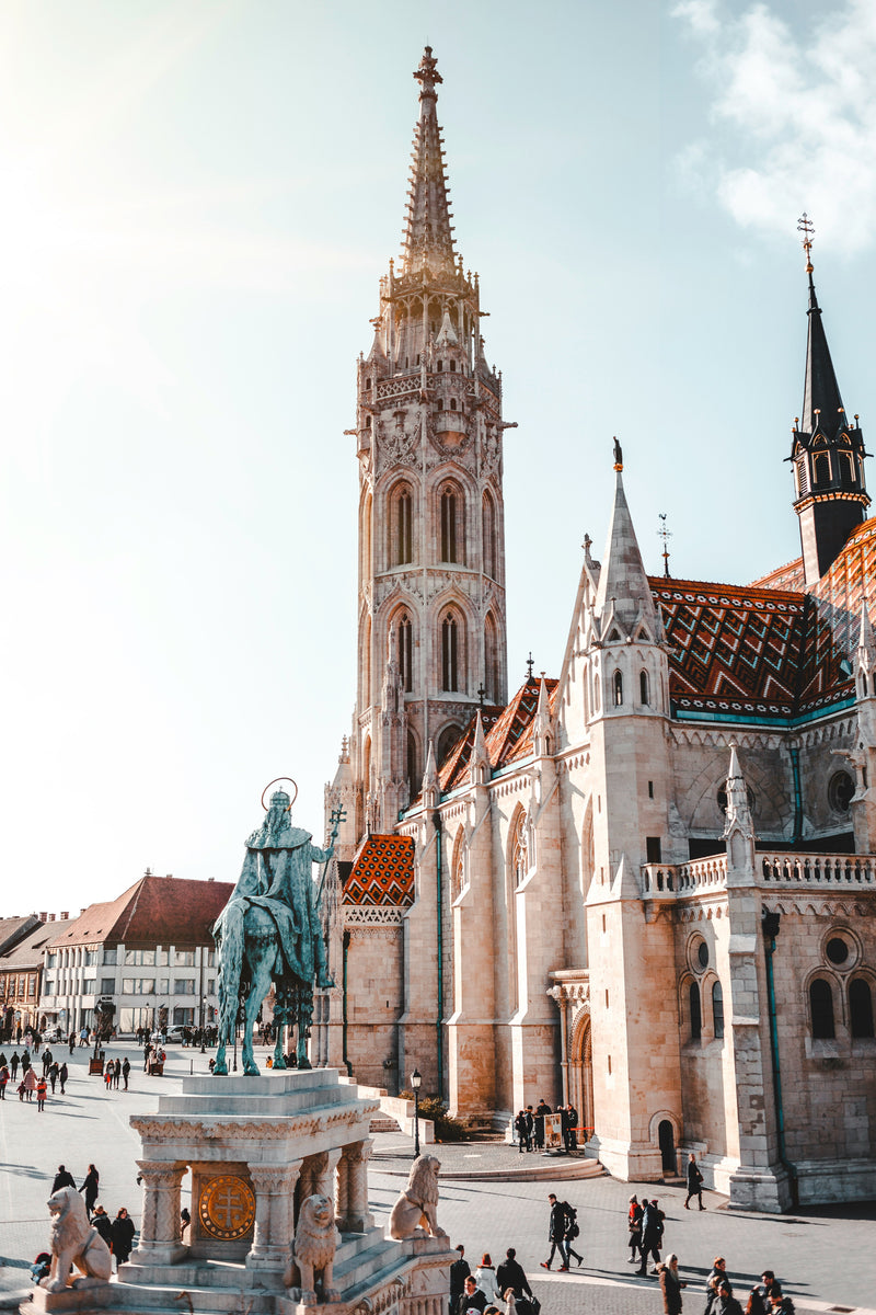 An ornate European church spire beside tiled rooftops and a stone terrace.