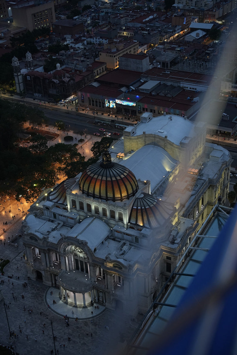 An illuminated domed building and surrounding Mexico City streets at dusk.