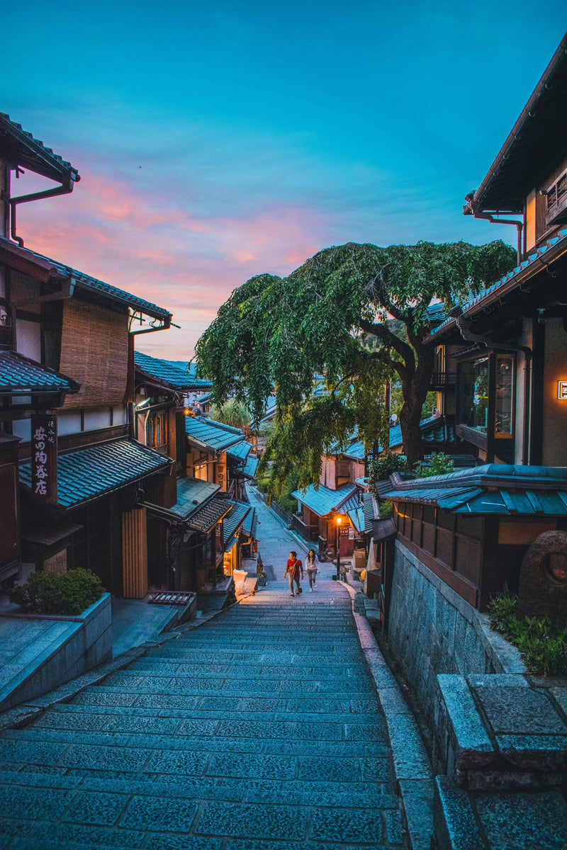 A stone-paved Japanese street lined with traditional wooden buildings at twilight.